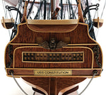 Wooden model of a ship's stern with 'USS Constitution' inscription, blurred background
