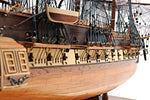Close-up of a wooden ship model with detailed rigging on a white background