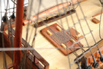 Close-up of a model ship's deck with wooden planks and metal grid