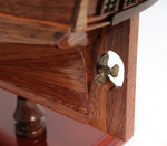 Close-up of a wooden model ship with a brass propeller on a white background