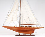 Wooden model sailboat with white sails on a white background