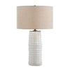 Table lamp with a textured beige shade and ribbed cylindrical base on a white background