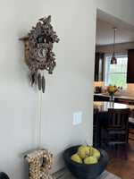 Cuckoo clock on a wall with a view of a kitchen in the background