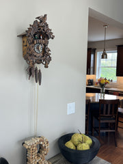 Cuckoo clock on a wall with a view of a kitchen in the background