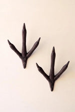 Two dark brown bird-trail wall hooks with small button eyes, shown on a plain off-white background.