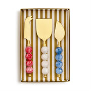 Set of three gold cheese knives with colorful bead handles in a striped box