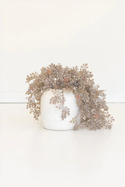 A white ceramic pot filled with cascading dried beige and brown foliage, photographed against a clean white background.