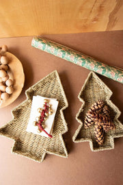 Two Christmas tree-shaped woven trays on a brown surface