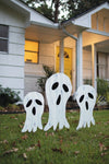 Three ghost decorations on a lawn in front of a house