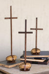 Three wooden cross sculptures on books against a neutral background