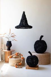 Decorative black pumpkins and witch hat on a white surface with a neutral background