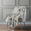 Decorative blanket with ship pattern draped over a chair in a room with gray walls.