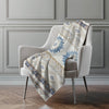 Patterned blanket draped over a chair against a gray paneled wall.