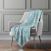 Light blue patterned blanket draped over a gray armchair against a gray wall.