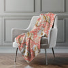 Coral blanket with shell pattern draped over a chair against a gray wall.