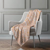 Patterned blanket draped over a gray armchair against a gray wall.