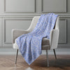 Blue patterned blanket draped over a gray armchair against a gray wall.