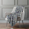 Patterned blanket draped over a chair against a gray wall.