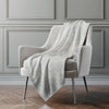 Gray blanket draped over a gray armchair against a gray wall.