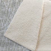 Close-up of a textured beige rug on a textured gray surface