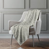 Light gray textured blanket draped over a white armchair against a gray paneled wall.
