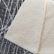 Close-up of a textured white rug with a contrasting patterned rug underneath.