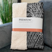 Folded blanket with 'Premium Washables' label on a gray surface