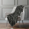 Zebra print blanket draped over a white chair against a gray paneled wall.