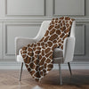 Giraffe patterned blanket draped over a chair against a gray wall.