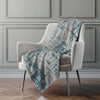 Gray armchair with a blue and gray patterned throw blanket against a gray wall.
