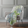 Decorative blanket with a leaf pattern draped over a chair in a room with gray walls.