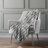 Patterned blanket draped over a chair in a room with gray walls.