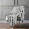 Gray textured blanket draped over a chair against a gray paneled wall.