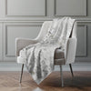 Floral-patterned blanket draped over a chair against a gray wall.