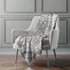 Patterned blanket draped over a chair against a gray wall.