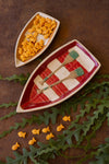 Two ceramic boat-shaped dishes with goldfish crackers and a checkered pattern on a brown background.