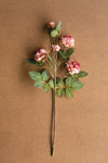 Artificial flower branch with pink flowers and green leaves on a brown background