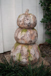 Decorative stone pumpkin stack with moss on a grassy background