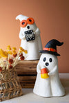 Two Halloween-themed ghost figurines with decorative items on a neutral background