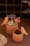 Terracotta teapot with flowers on a wooden surface