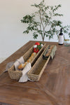Two woven bread baskets on a wooden table with bread, tomatoes, and a bottle of wine.