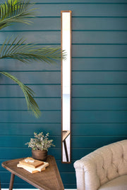 Tall vertical mirror on a blue wall with a plant and sofa in the foreground