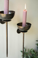 Two black candle holders with pink candles against a light background