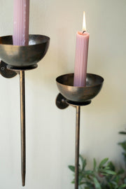 Two black candle holders with pink candles against a light background