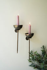 Two candle holders with pink candles against a light background