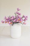 White vase with purple flowers on a light background