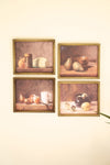 Four framed still life paintings on a wall