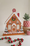 Decorative gingerbread house with festive decorations on a white surface.