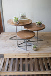 Set of three wooden nesting tables with glass containers on a wooden surface.