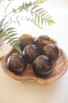 Brown spherical objects on a wooden tray with ferns in the background